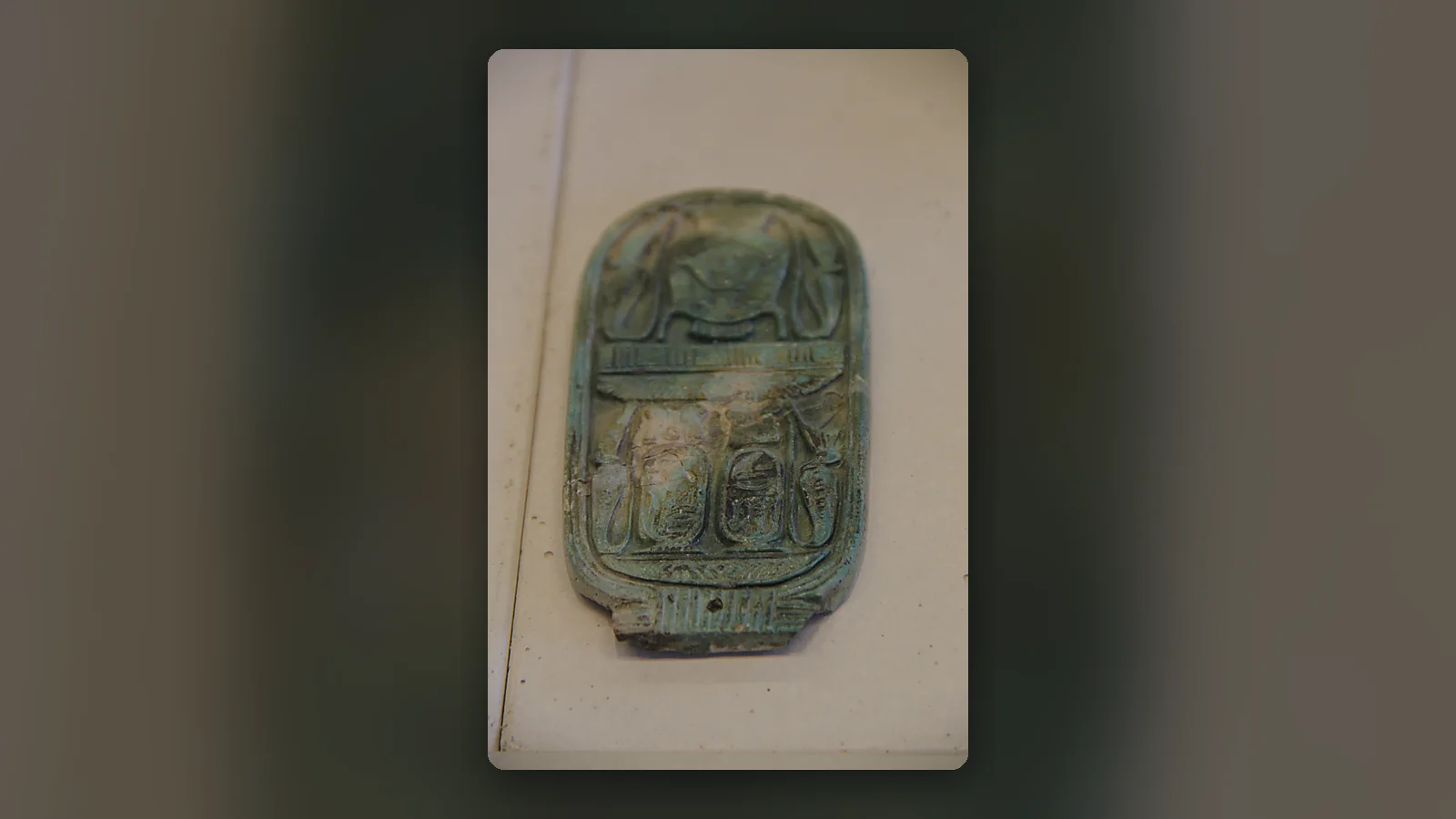 Amulette égyptienne ancienne en faïence turquoise présentée sur un fond sobre et lumineux.